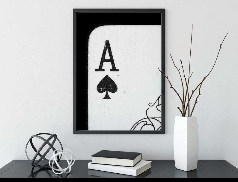 Op de afbeelding: Zwart-wit ingelijste print van een aas schoppen speelkaart. De kaart is gedeeltelijk zichtbaar met de aas en schoppen symbool in het midden van de print.