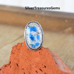 May include: A silver ring with a blue and white oval-shaped stone. The stone has a unique pattern of blue and white.