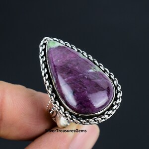 Puede incluir: Un anillo de plata con una gran piedra preciosa de color púrpura y verde en forma de lágrima, engastada en una banda de plata trenzada.