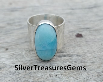 May include: A silver ring with a light blue oval cabochon gemstone. The ring band is textured and has a hammered finish.