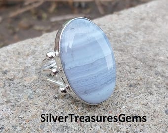 Könnte beinhalten: Ein Silberring mit einem großen, ovalen, hellblauen Edelstein. Der Stein hat ein gebändertes Muster und ist in einem Silberband mit dekorativen Details gefasst. Der Text "SilverTreasuresGems" ist unten sichtbar.