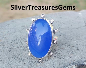 Könnte beinhalten: Ein silberner Ring mit einem großen, ovalen blauen Edelstein, der in einem dekorativen, sternenförmigen Design gefasst ist.