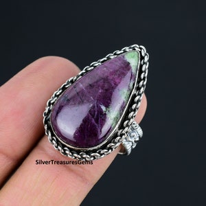 May include: A silver ring featuring a large, teardrop-shaped purple and green gemstone set in an intricate silver bezel.