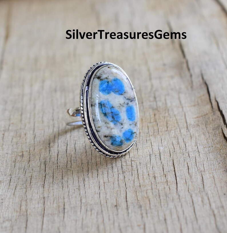 May include: A silver ring with a blue and white oval gemstone. The gemstone has a unique pattern of blue spots on a white background.