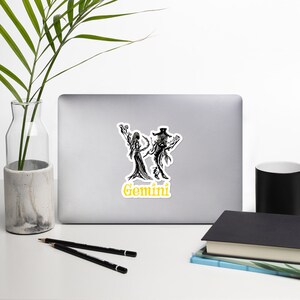 Puede incluir: Ilustración en blanco y negro del signo del zodíaco Géminis con la palabra "Géminis" en texto amarillo.
