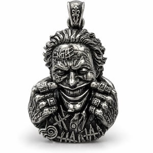 May include: A silver-toned metal pendant shaped as a bust of a grinning character with messy hair, facial scars, and tattoos on the forehead and hands. The figure wears rings on its fingers and has a textured, weathered finish with dark oxidation.