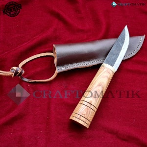 May include: A handmade knife with a wooden handle and a leather sheath. The knife has a dark gray blade and a brown wooden handle with a light brown stripe pattern. The sheath is brown leather with a stitched edge.