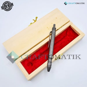 May include: A silver pen with a textured finish is displayed in a wooden box with a red velvet lining. The box has a brass latch and the text "CRAFTOMATIK" is visible on the box. The pen is labeled "ORIGINAL HAND MADE ORIGINAL".