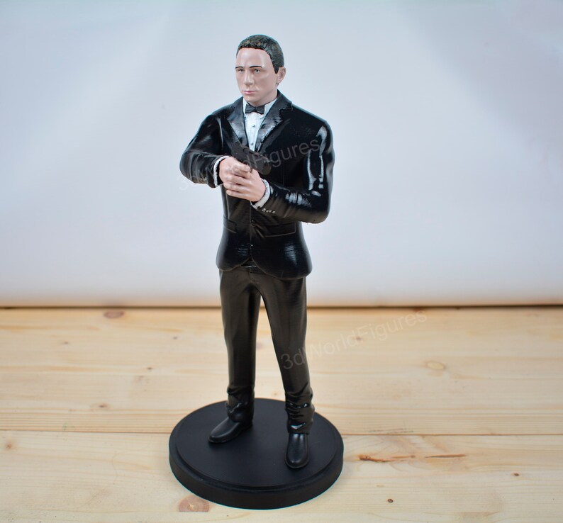 Pu&ograve; includere: Statuetta di un uomo in smoking nero, camicia bianca e papillon nero. La figura &egrave; in piedi su una base circolare nera. L'uomo tiene le mani giunte davanti a s&eacute;. La statuetta &egrave; un oggetto da collezione.