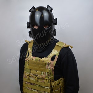 May include: A person wearing a black tactical helmet with a face shield and a camouflage tactical vest.