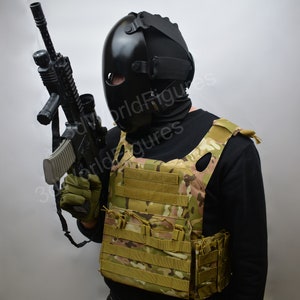 May include: A person wearing a black tactical helmet and a black balaclava holds a black rifle with a scope. The person is wearing a tan tactical vest with multiple pouches.