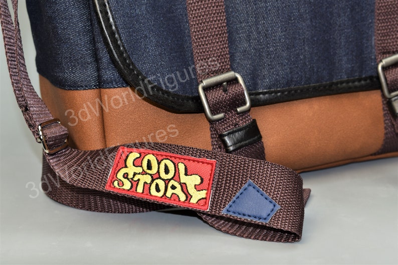 May include: A brown and dark blue messenger bag with a brown adjustable strap. The strap has a red patch with the words "Cool Story" in yellow lettering.
