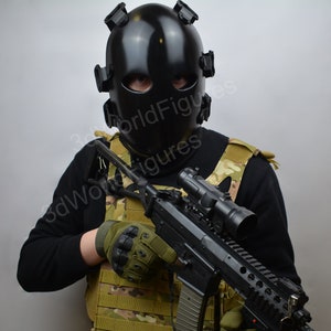 May include: A person wearing a black tactical helmet and a camouflage vest holds a black rifle with a scope.