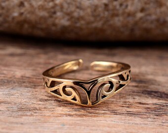 May include: A gold-toned toe ring with a delicate, intricate design. The ring is open and adjustable to fit most toe sizes.