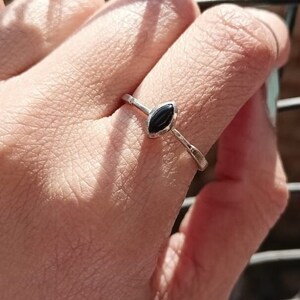 May include: A silver ring with a black oval-shaped gemstone.