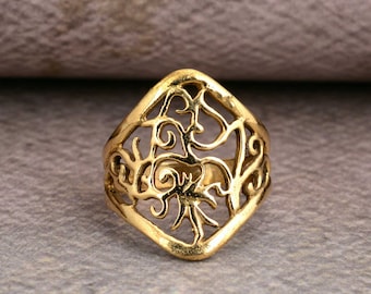 May include: A gold-toned ring with a delicate, intricate design. The ring is made of a thin metal and has a diamond shape.