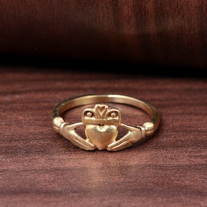 Op de afbeelding: Een gouden Claddagh-ring met een hart, handen en kroonontwerp.