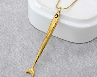Op de afbeelding: Een gouden vis-hangerketting met een ketting. De hanger is lang en dun, met een gedetailleerd visontwerp. De ketting is delicaat en heeft een karabijnhaak.