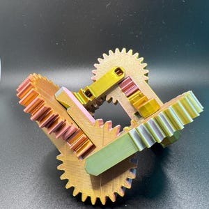 Puede incluir: Un complejo mecanismo de engranajes multicolor con engranajes entrelazados. Los engranajes son principalmente dorados con acentos rosas, verdes y amarillos. El diseño sugiere un tema mecánico o de ingeniería.