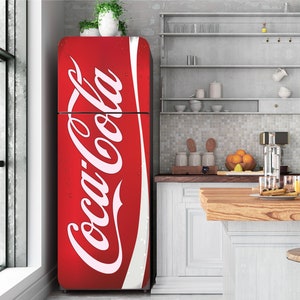 Puede incluir: Un refrigerador rojo con un logotipo blanco de Coca-Cola en la parte delantera. El refrigerador está en una cocina con una encimera de madera y gabinetes blancos.