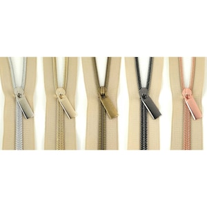 May include: Five beige zipper tapes with different colored metal zipper pulls. The pulls are silver, gold, bronze, black, and rose gold.