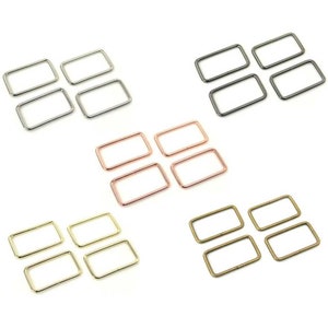 May include: Four sets of four metal D-rings in different finishes: silver, rose gold, gold, and bronze. Each set of D-rings is arranged in a square shape.