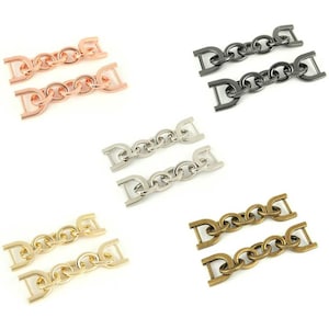 May include: Two pairs of metal chain connectors in four different finishes: rose gold, silver, black, and antique brass. Each connector has two D-shaped rings connected by a chain.