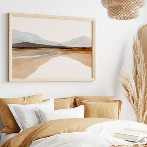 May include: A bedroom with a bed dressed in beige linens and a framed abstract landscape painting above the headboard. The room features a woven headboard and a dried pampas grass arrangement in a woven vase.