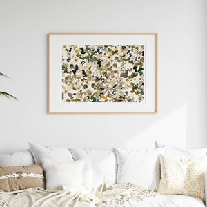 May include: A framed abstract print with a white background and a pattern of brown, green, and yellow shapes.