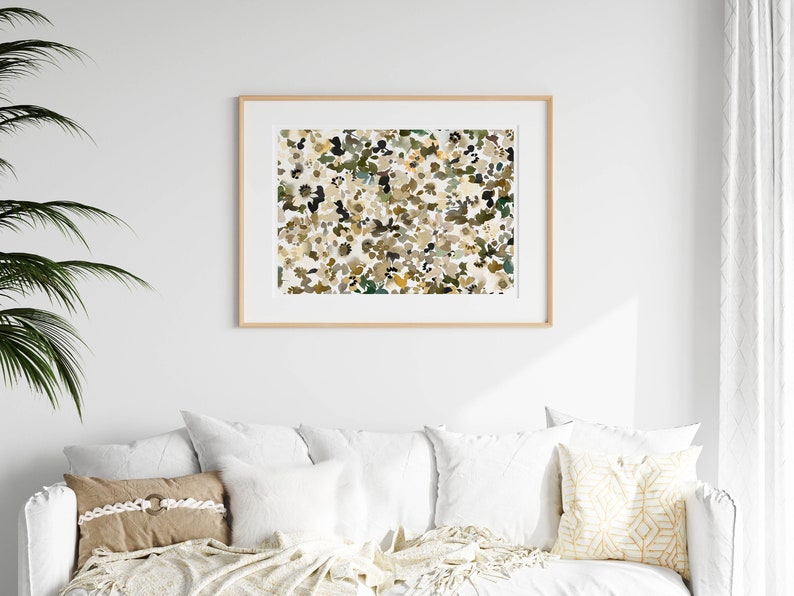May include: A framed abstract print with a white background and a pattern of brown, green, and yellow shapes.