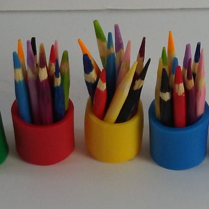 May include: Five colourful pencil holders, each filled with a variety of coloured pencils. The holders are green, red, yellow, blue, and purple.