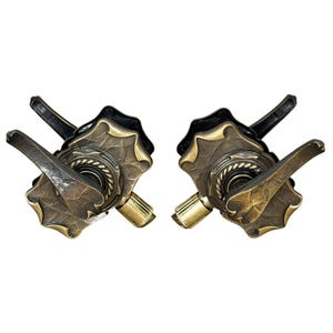 May include: Two matching door handles featuring a dark, hammered bronze finish with a textured, scalloped rectangular backplate. Each handle includes a central rope-style ring detail, a curved lever, and a small, smooth cylindrical brass-toned knob.