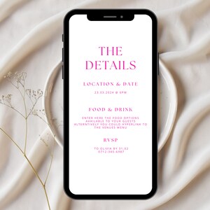 May include: A smartphone displays event details in pink text against a white background. The text reads "THE DETAILS," followed by location, date, and time. Additional text includes "FOOD & DRINK" and RSVP information. The phone rests on a white plate, with a beige fabric backdrop.