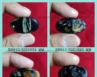 May include: Four oval-shaped black, white, and brown gemstone cabochons. The gemstones are approximately 30mm x 19mm and 32mm x 20mm. Each gemstone is held in a hand and photographed against a red background.