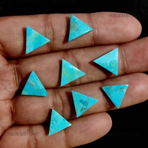 Peut inclure: Huit pierres précieuses triangulaires en turquoise avec veinage naturel sont présentées. Les pierres sont d'un bleu-vert vibrant, avec des variations de tons et de textures. Les pierres sont disposées sur une surface sombre.