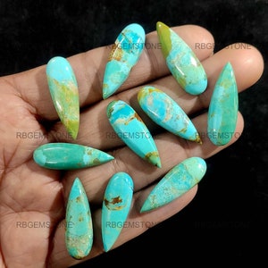 May include: A collection of ten turquoise cabochons in a teardrop shape. The stones are a mix of blue and green with brown and gold inclusions.
