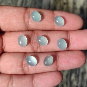 May include: Seven oval-shaped, light blue gemstones with a smooth, polished finish.