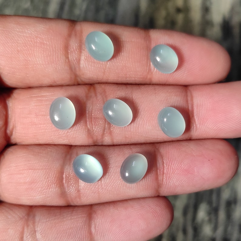 May include: Seven oval-shaped, light blue gemstones with a smooth, polished finish.
