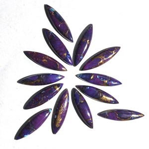May include: A collection of 12 purple and gold cabochons, arranged in a starburst pattern. The cabochons are oval shaped and have a marbled appearance.