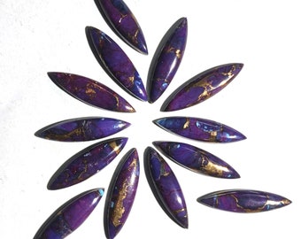 May include: A collection of 12 purple and gold cabochons, arranged in a starburst pattern. The cabochons are oval shaped and have a marbled appearance.