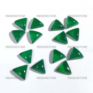 Puede incluir: Doce piedras preciosas cabujón triangulares verdes, cada una con una superficie lisa y pulida. Las piedras preciosas están dispuestas en un patrón aleatorio sobre un fondo blanco.