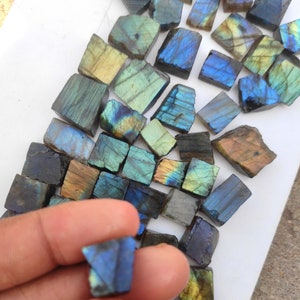 Può includere: Una collezione di schegge di labradorite, una pietra preziosa iridescente, in varie tonalità di blu, verde e oro. Le schegge hanno una forma irregolare e una texture naturale e grezza.