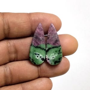 Può includere: Due cabochon a forma di goccia con una distinta separazione di colore tra il rosa magenta intenso e il verde bosco screziato con inclusioni nere. Queste pietre levigate presentano una superficie liscia e arrotondata con punta.