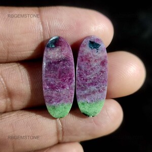Peut inclure: Deux pierres précieuses ovales avec un dégradé de couleurs saisissant. La partie supérieure est d'un magenta profond, passant à une teinte plus claire et se terminant par une base vert vif. Chaque pierre a une inclusion bleu foncé en haut.