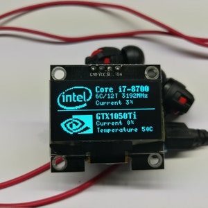 May include: A small blue LCD screen displays system information, including the text "Core i7-8700", "6C/12T 3192MHz", "Current 3%", "GTX1050Ti", "Current 0%", and "Temperature 50C". The screen is mounted on a black circuit board with four small black screws.