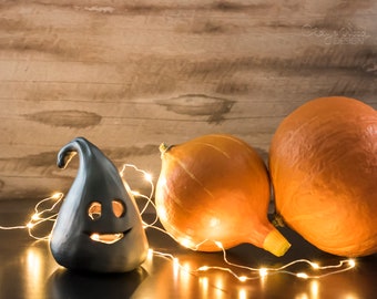 Halloween decor. Silvery black ceramic ghosts. Lantern with cute pumpkin eyes. Fall season decoration.
