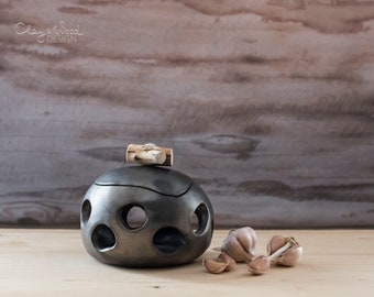 Black ceramic pot with holes and cover for onions and garlics or handicraft stuff. Black pottery without ceramic glaze.  Nordic, minimalism.