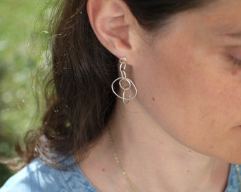 May include: Silver dangle earrings with a geometric design of interlocking circles.