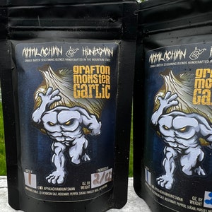 May include: Two black resealable pouches of Appalachian Huntsman small batch seasoning blends. The front of each pouch features a cartoon monster holding a large clove of garlic. The text on the pouch reads "Grafton Monster Garlic".