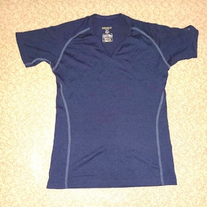 Puede incluir: Una camiseta azul marino de manga corta y cuello en V con una pequeña etiqueta que dice "REVOLV" en la parte delantera.